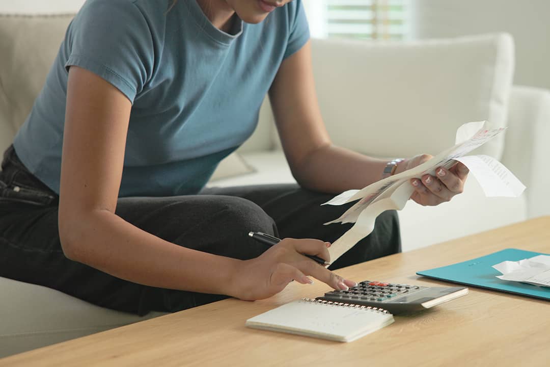 A woman at home calculating bills and expenses.